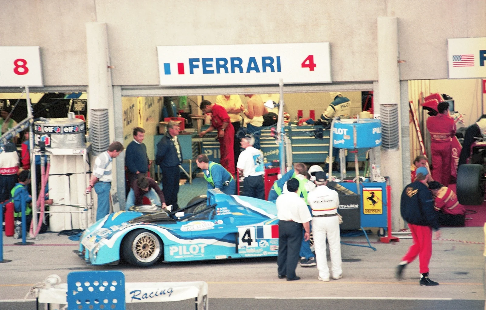 A race crew preparing a blue prototype outside its garage.