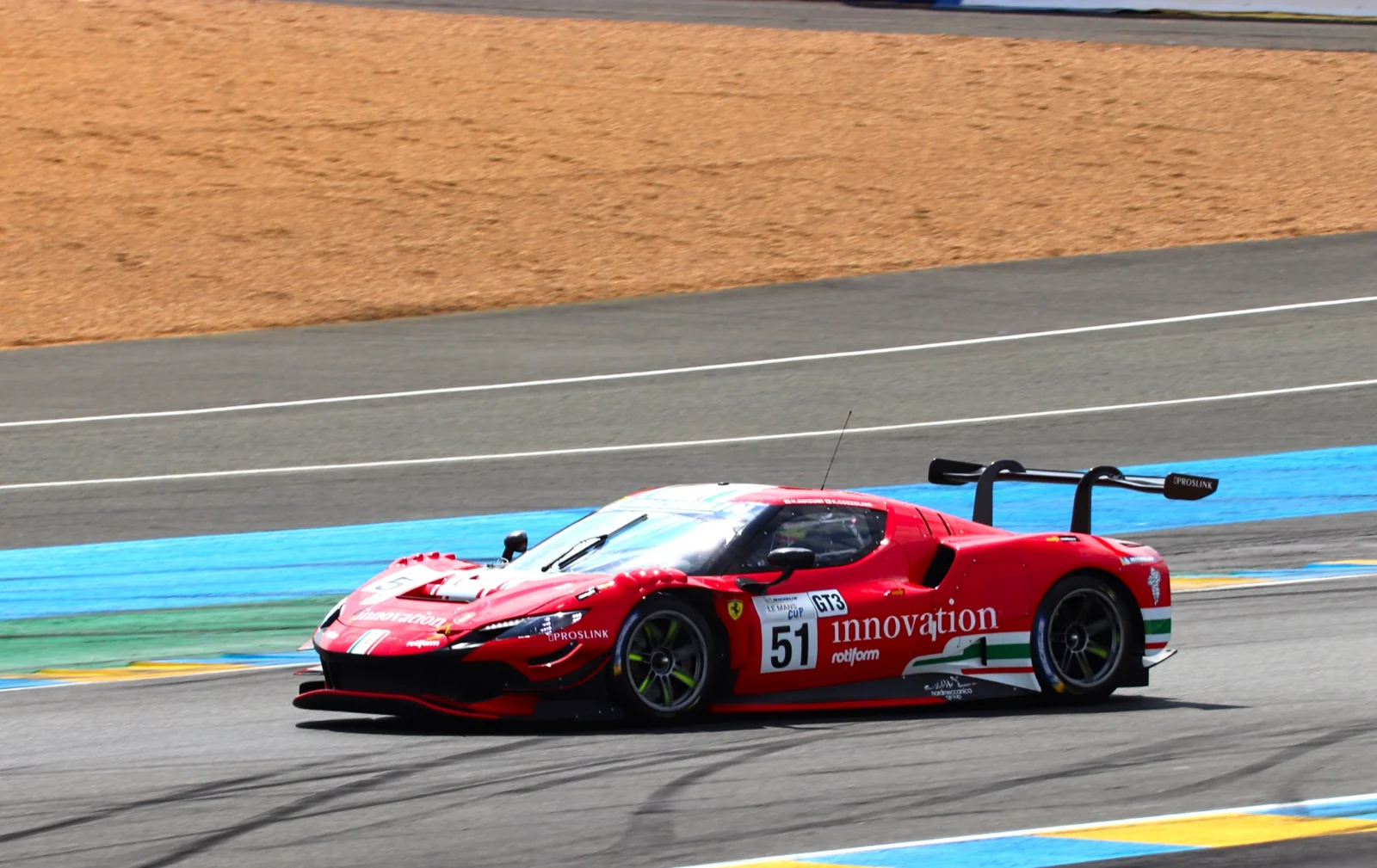A red GT race car on circuit.