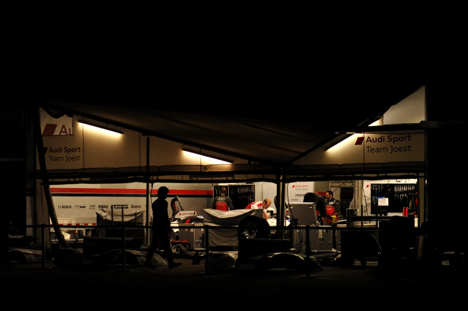 An illuminated race-team garage after dark.
