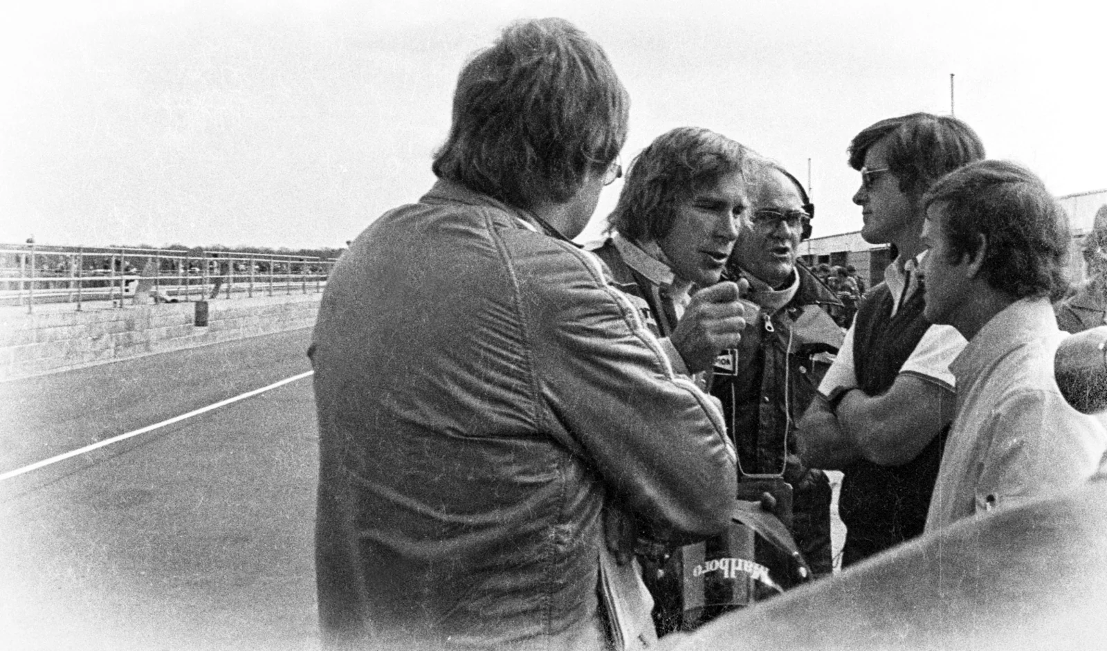 An archival black-and-white photograph of a conversation in the paddock.