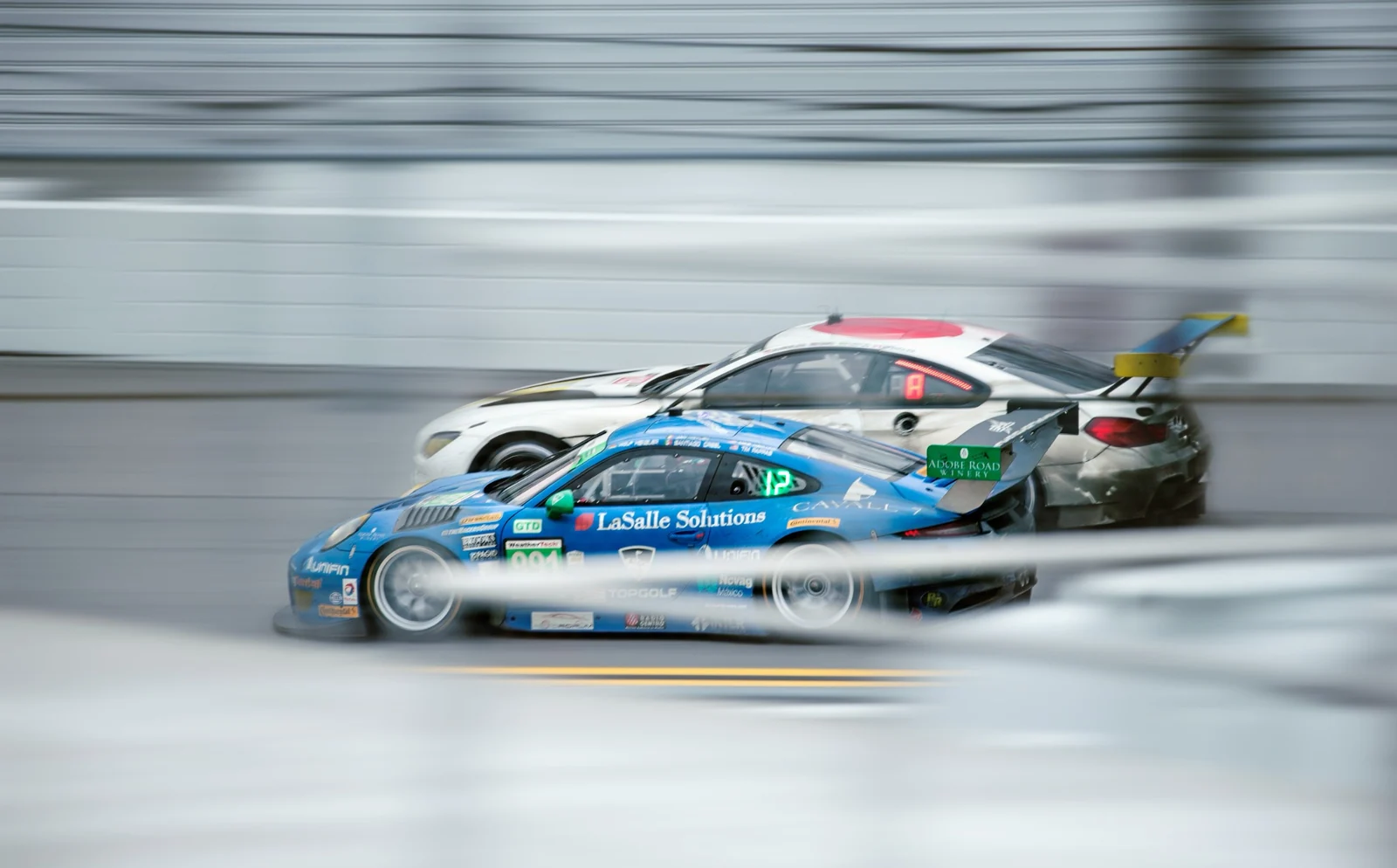 Two GT race cars side by side on a circuit.