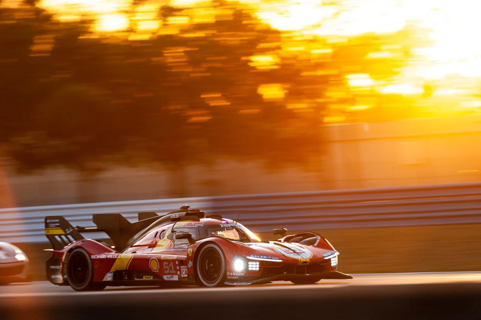 An endurance race car on track in golden evening light.